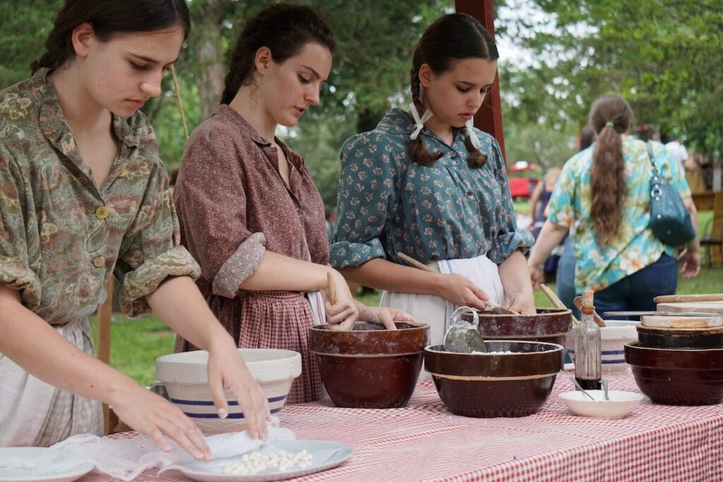 Pennsylvania Dutch women preparing traditional food at an outdoor community event.